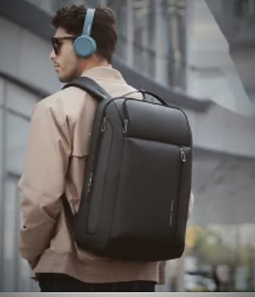 A black nylon commuter backpack worn on a city street