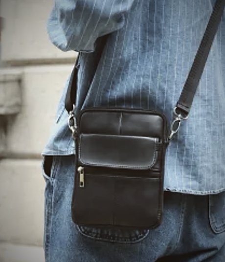 A black leather crossbody bag worn over denim